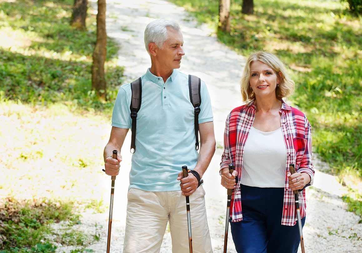Active seniors Portrait of senior couple enjoying a nordic walk. Active elderly woman and man walking on the forest and smiling.